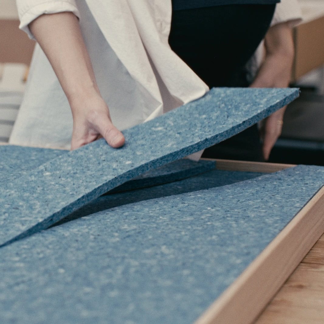 Hands assembling multi-layer acoustic panels designed for sound absorption inside a room.